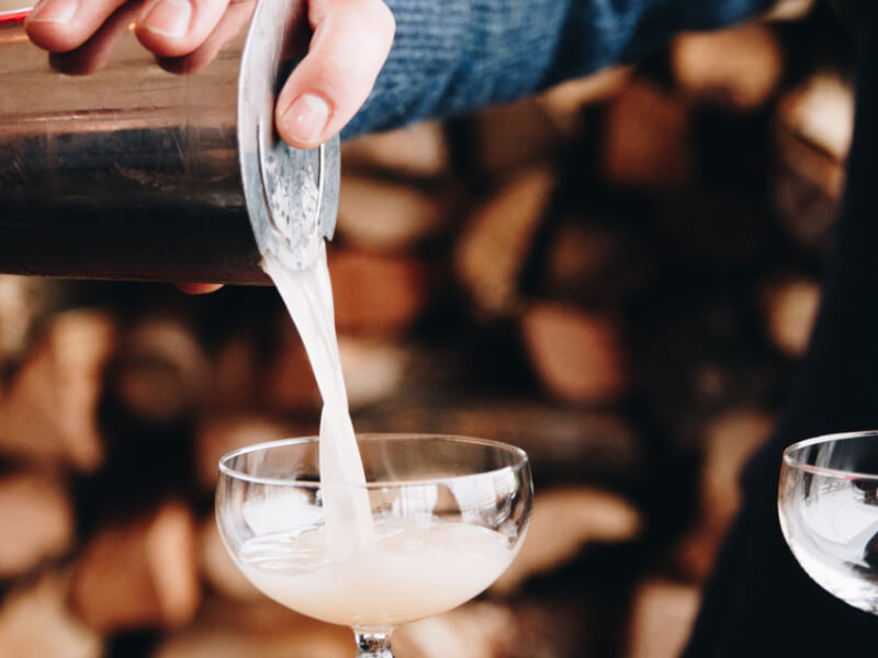 close up of straining a cocktail into a glass